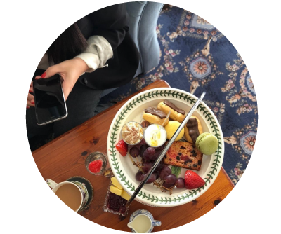 Woman holds phone ready to capture here afternoon tea selection at home 