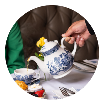 A hand pouring a chine pot of tea into a mug, afternoon tea