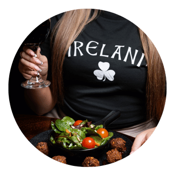 Girl wearing Ireland T-shirt holds glass of wine in front of Vegan Falafel Salad