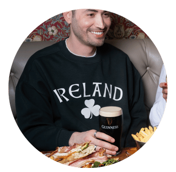 Young Man in Ireland T Shirt smiles while holding a pint
