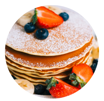 Pancake Tuesday Stack with strawberries, blueberries and sauce oozing over the top
