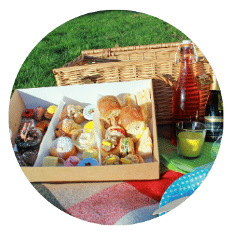 Picnic Hamper with Old Music Shop Restaurant Afternoon Tea Alfresco Box with sandwiches, scones and desserts. Bottle of rose and snipe of prosecco with yellow candle on Foxford rug. Dublin Ireland