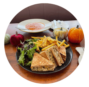 Chicken and Stuffing Sandwich toasted served with mixed leaves and skinny fries. Decorative pumpkins and soup and cutlery 