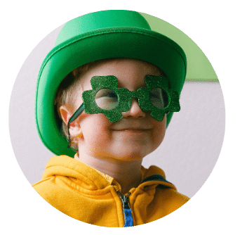 Smiling Toddler Boy in green hat and shamrock glasses for St Patricks Day Photo Credit Anna Shvets