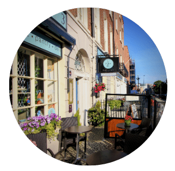 Street View of Exterior of Old Music Shop Restaurant Door and street outdoor dining tables, flower boxes and signage